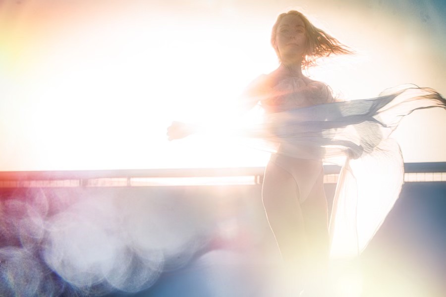 Becca spinning with sheer fabric in a haze of golden sun-flare