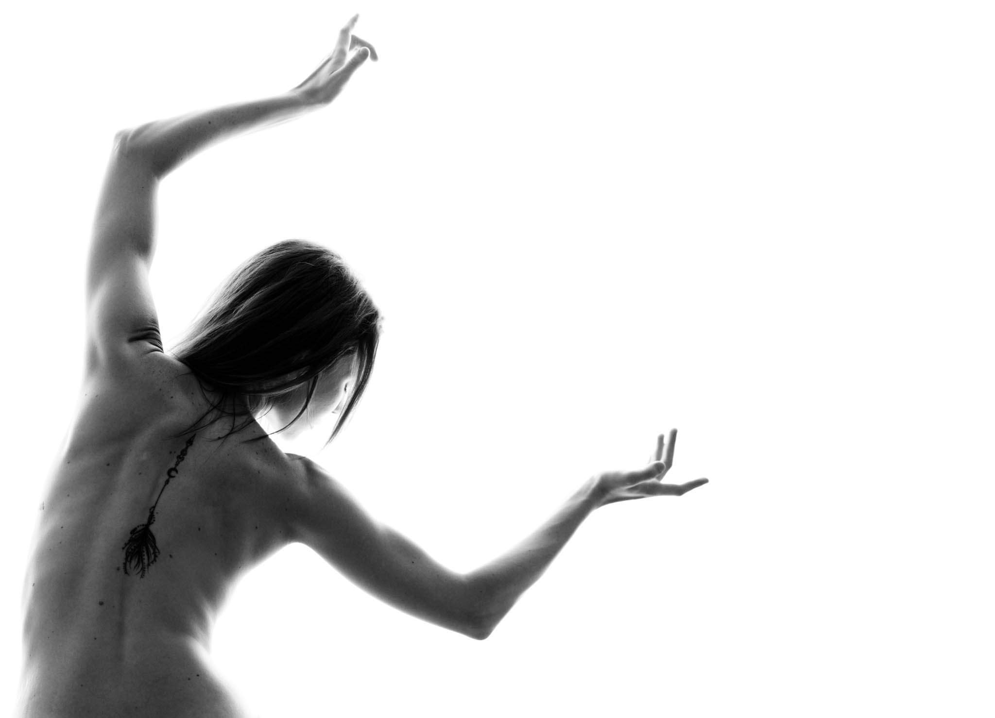 Becca mid-leap, arched back against a white wall — black-and-white artistic portrait